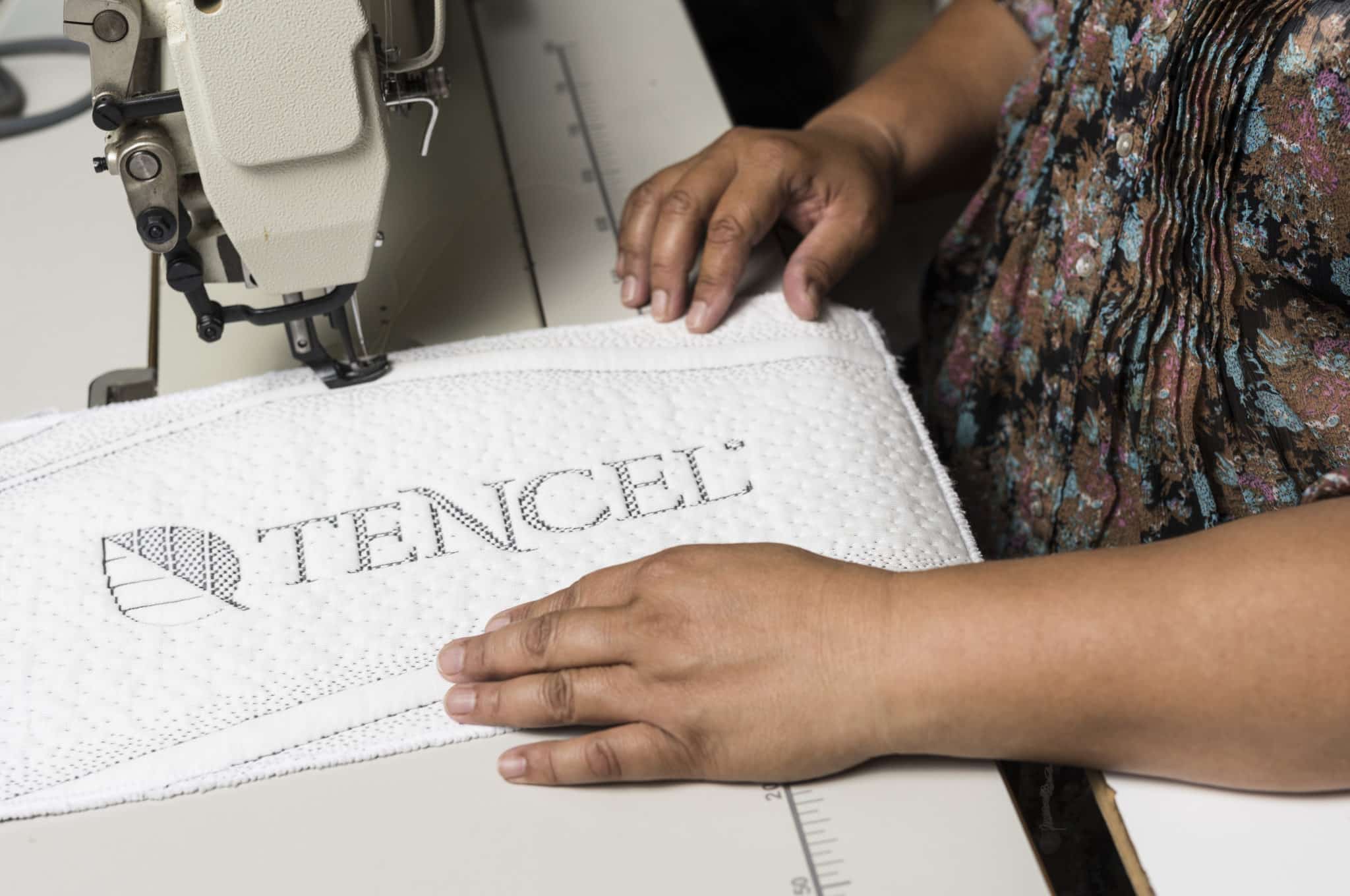 A woman sewing a Tencel mattress cover using a sewing machine